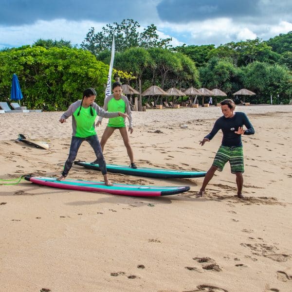 Surf instructor giving a lesson to students on the beach.