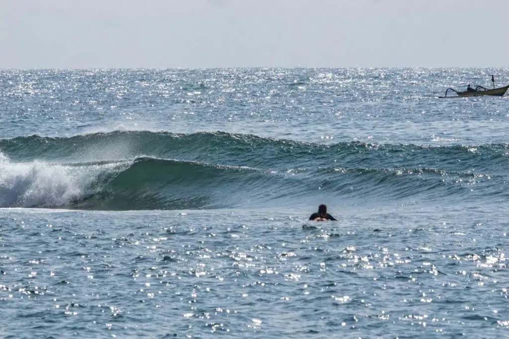 A surfer paddling out to waves at Mengiat.