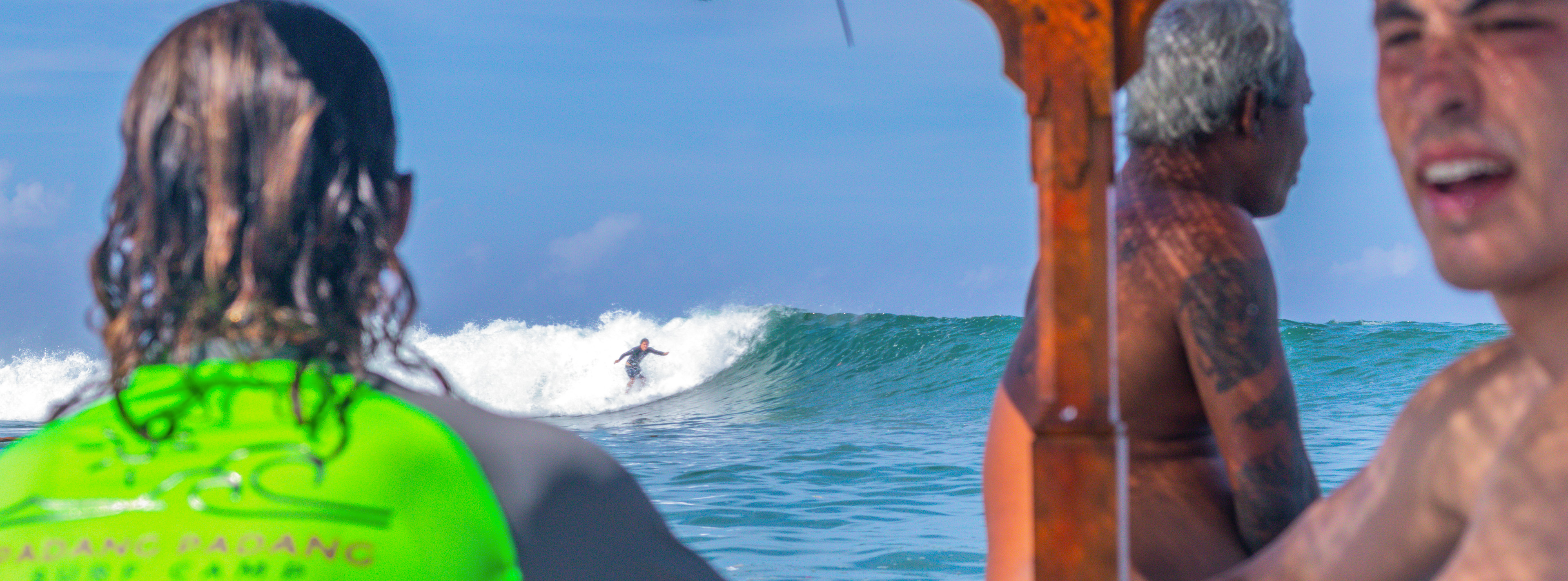 Surfer riding a wave as an instructor looks on from the boat.